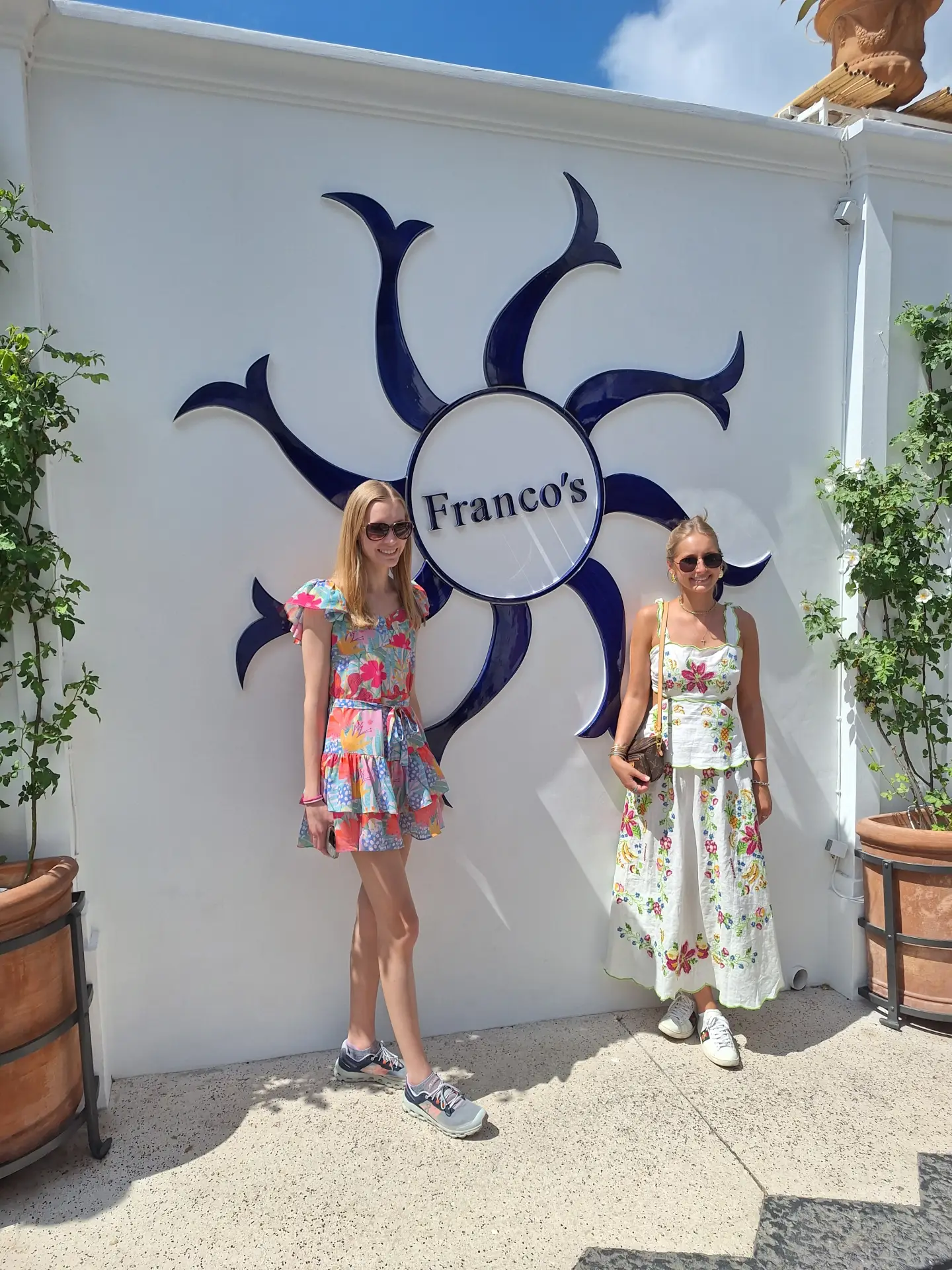 Two women posing in front of a stylish Franco's sign in Amalfi