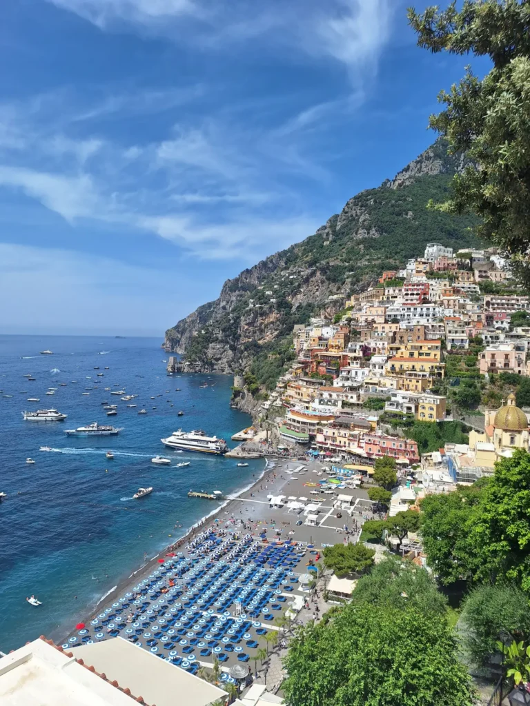 Amalfi beach with vibrant umbrellas and scenic coastline under a bright blue sky