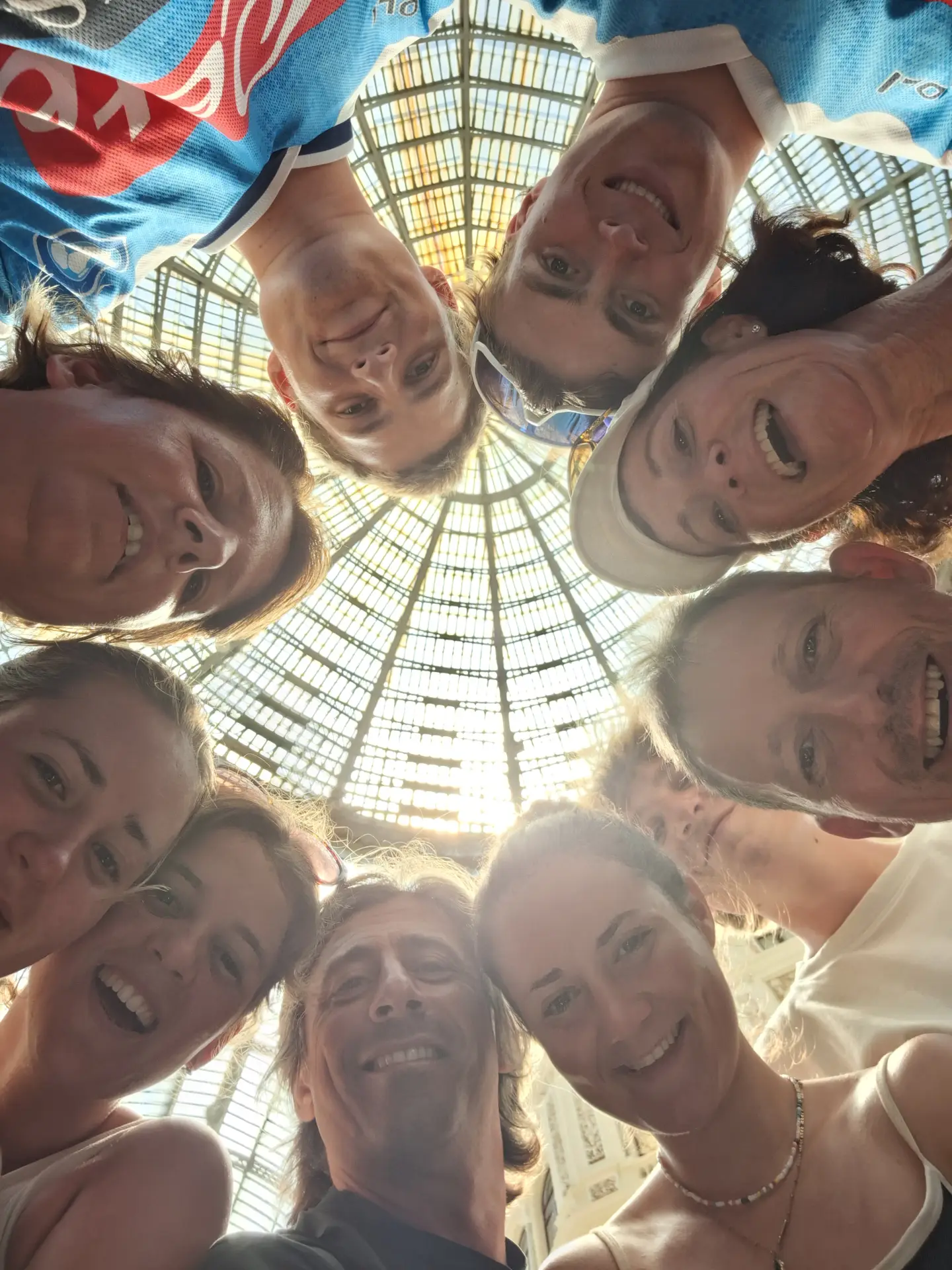 A group of tourists taking a circular selfie under the glass dome of the Galleria Umberto I in Naples