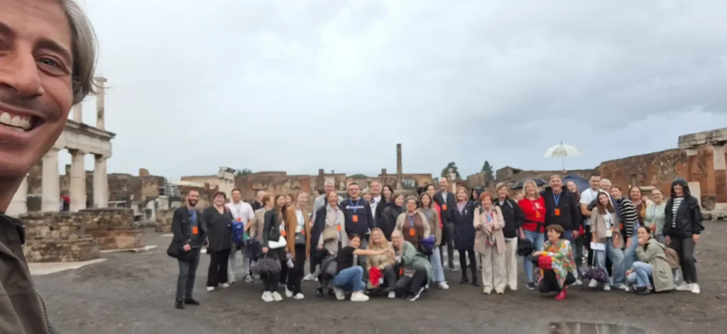 A large group of tourists gathers for a memorable photo during their immersive tour of Pompeii’s historic streets and landmarks