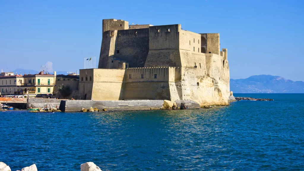 View of Castello dell'Ovo overlooking the sea, with the blue sky and mountains in the background