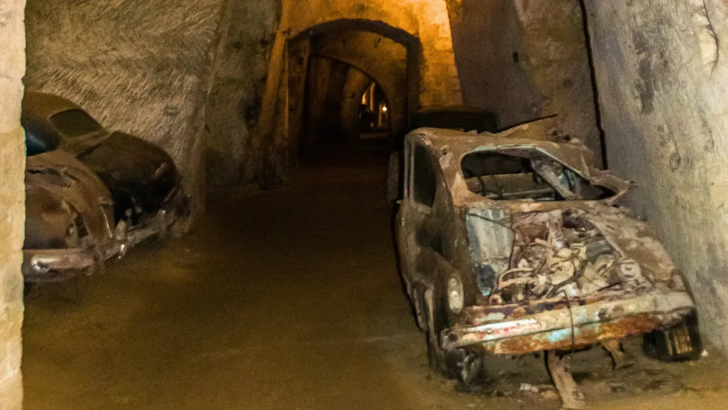 Tunnel inside the Galleria Borbonica, featuring a vintage car and a glimpse of the underground passageway