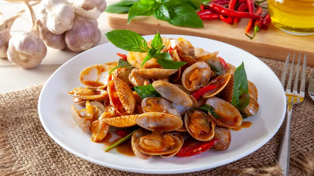 Close-up of a plate of pasta with clams, garnished with fresh basil and chili peppers